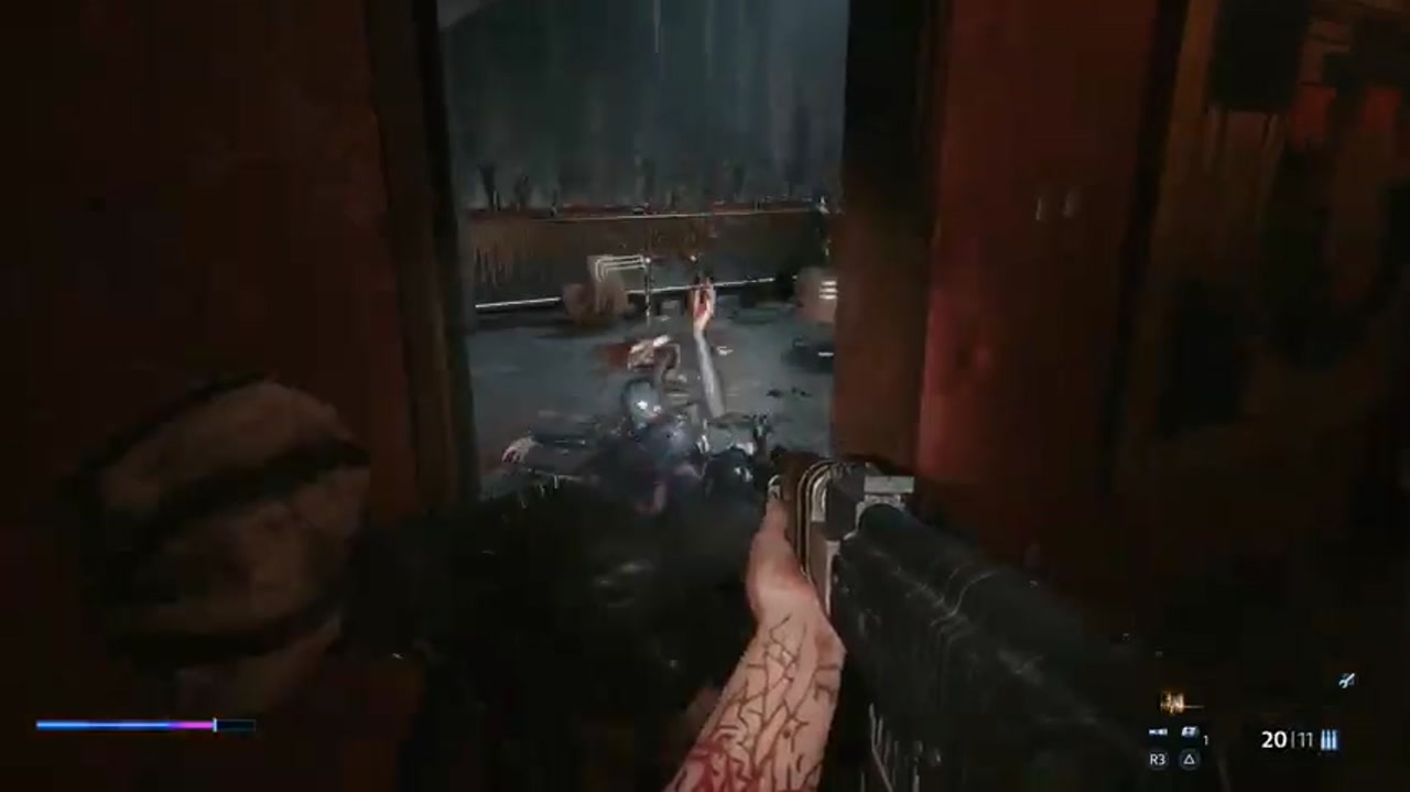 Aiden apunta con una ametralladora a una puerta con un enemigo mutilado detrás, en Hellraiser: Revival.