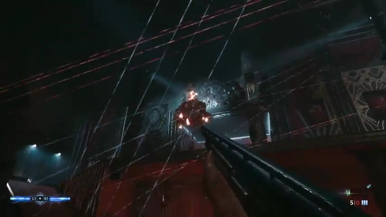 Aiden apunta con una escopeta hacia arriba a una bola en llamas debajo del techo de un club con rayos láser en Hellraiser: Revival.